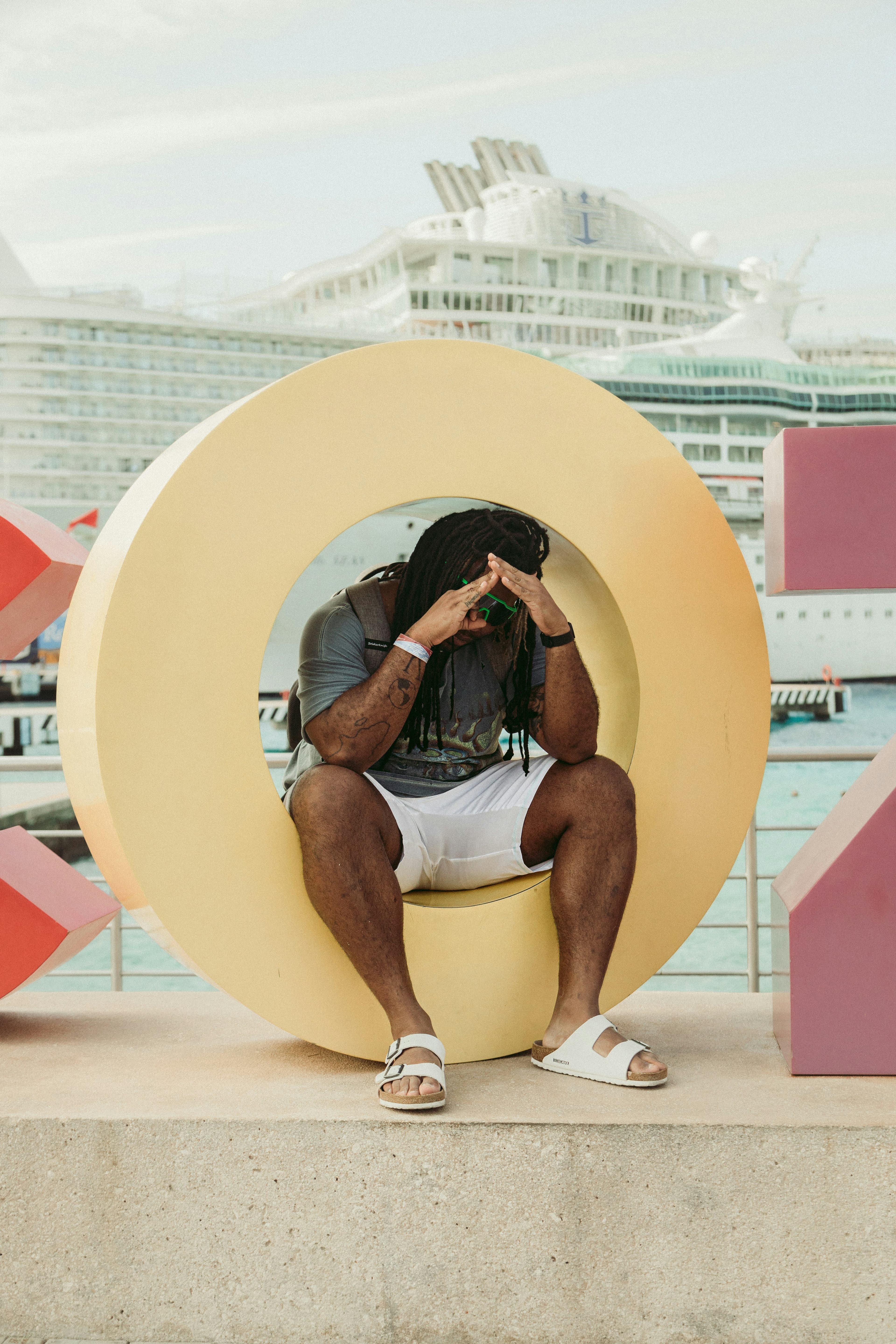Man sitting inside a large letter O sculpture