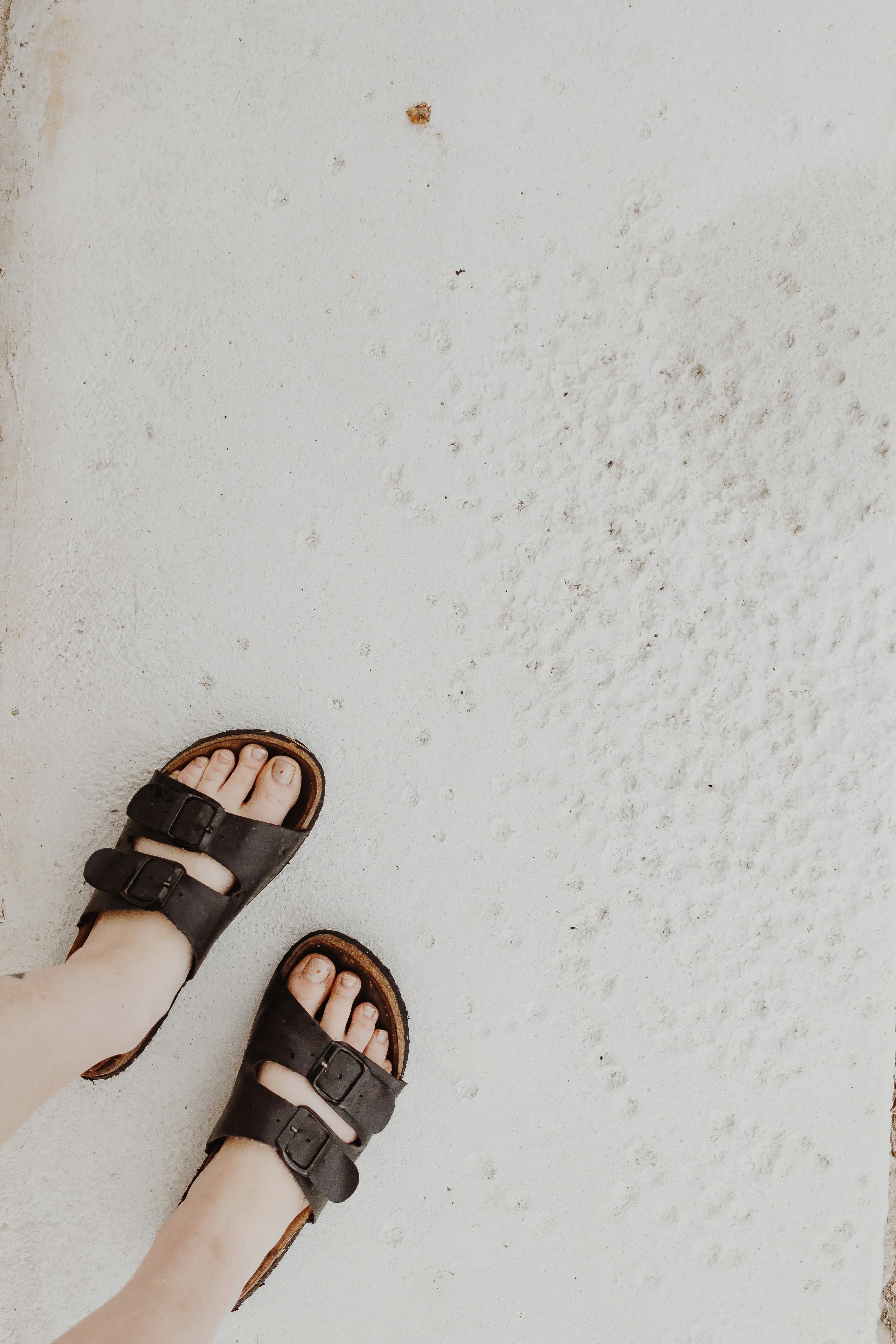 Feet in black leather slides on a white floor