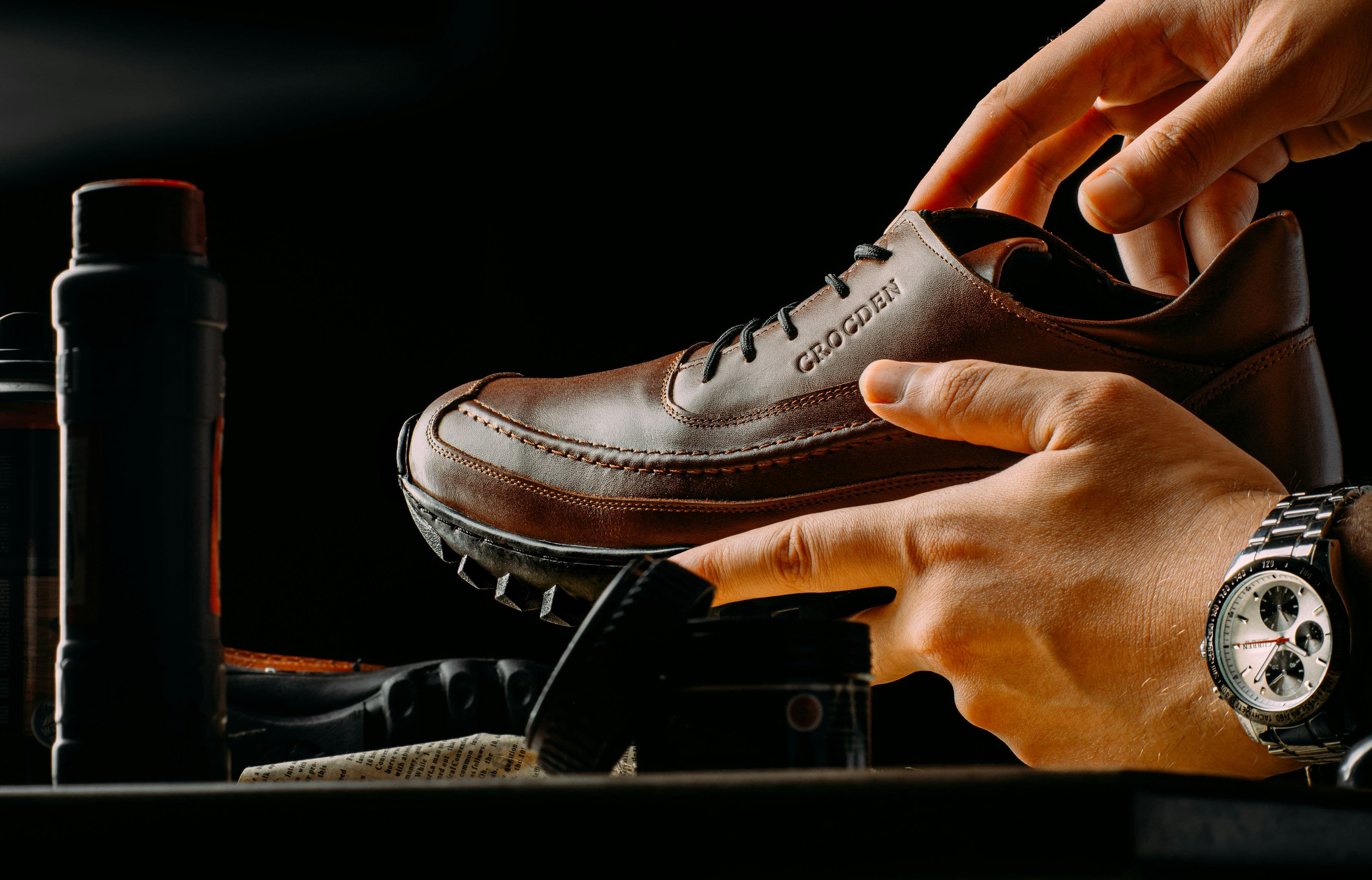 Hands finishing a pair of brown shoes