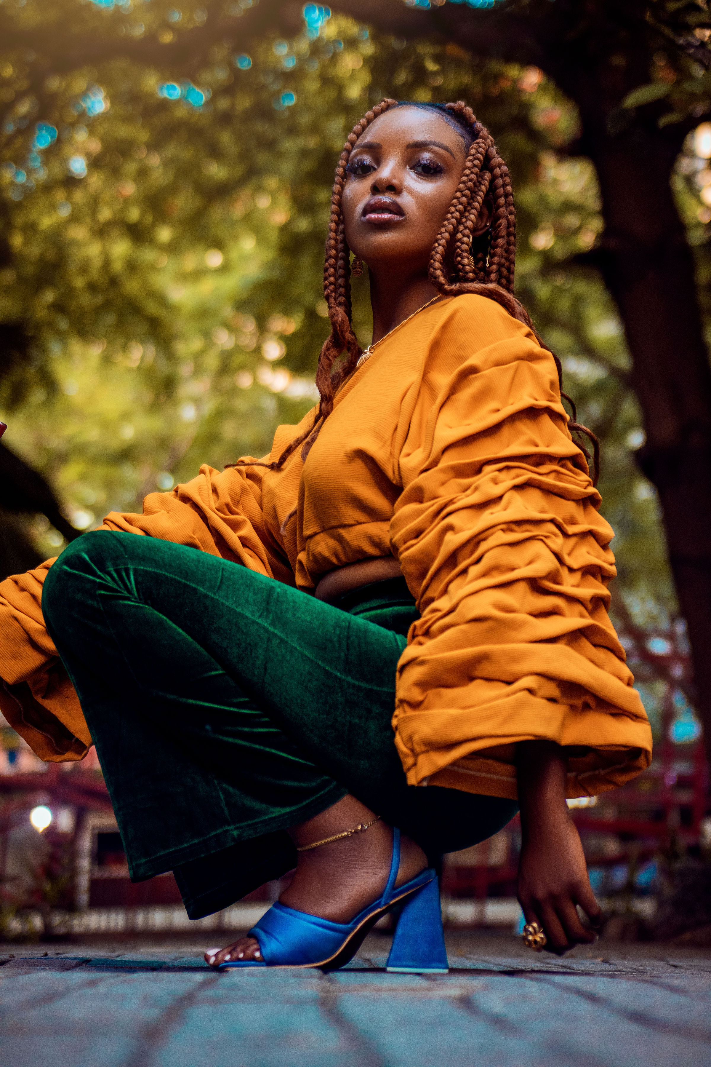 Woman in an orange top crouching on a city street