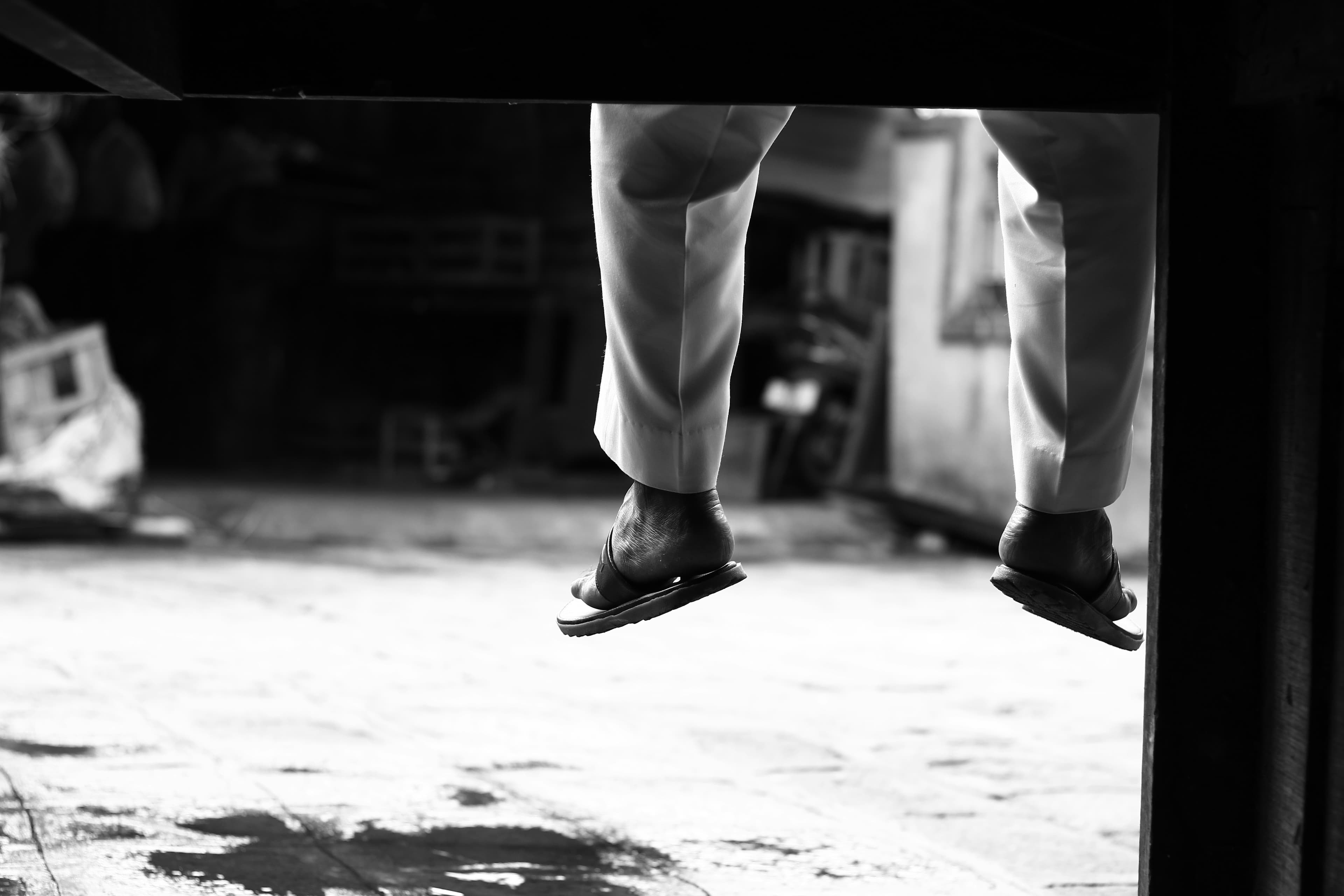 Feet in slides hanging from a ledge, black and white