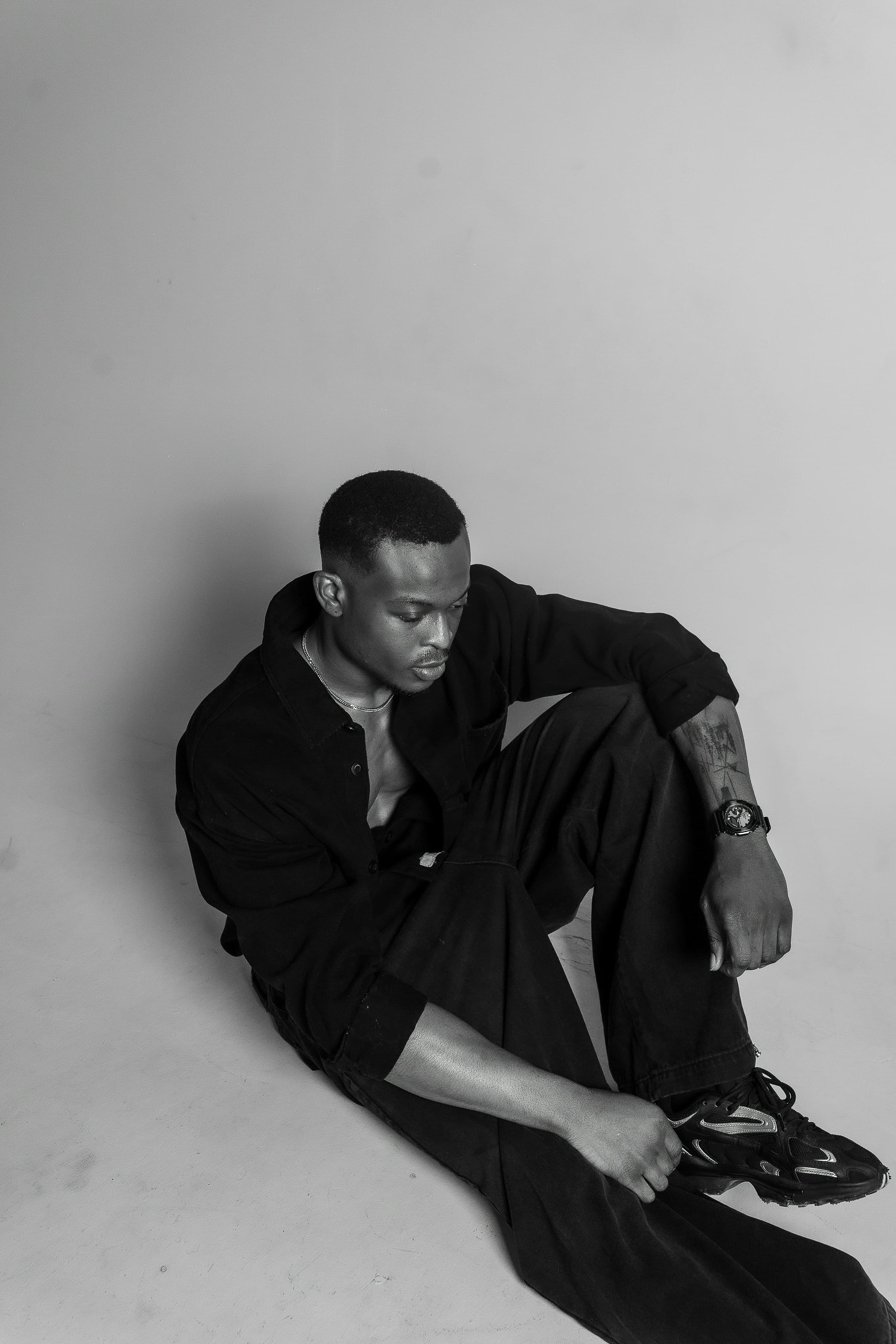 Man in black sitting on the floor, black and white