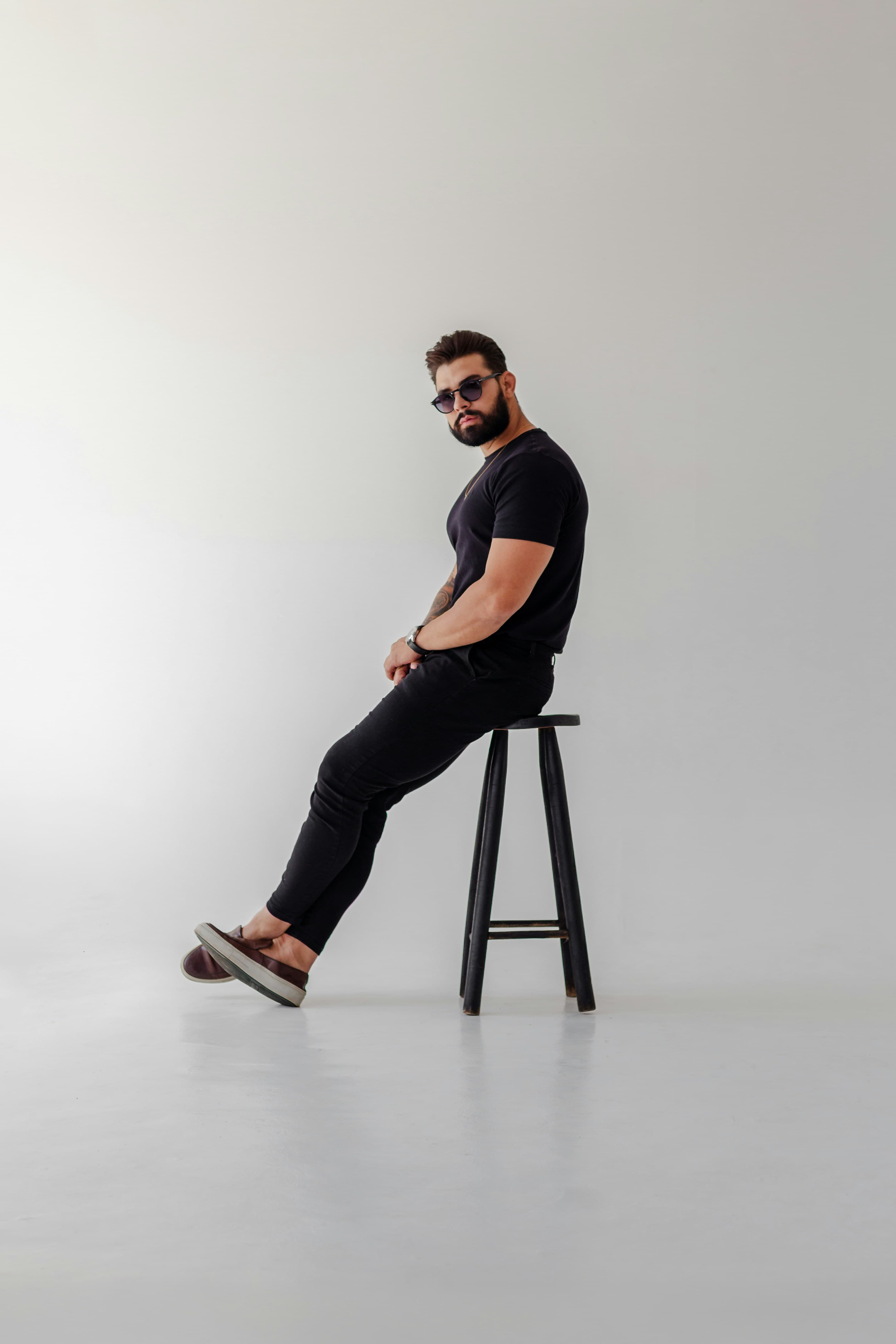 Bearded man in sunglasses on a black stool